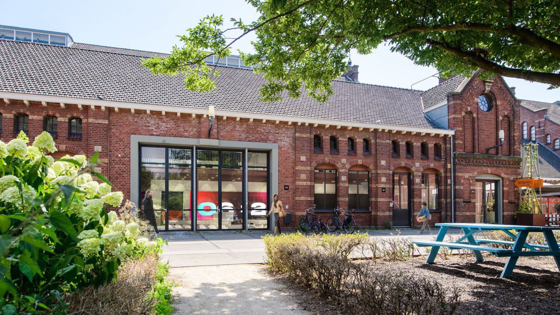 Exterior view of a red brick building at Westergasfabriek in Amsterdam, with large glass windows and traditional architecture